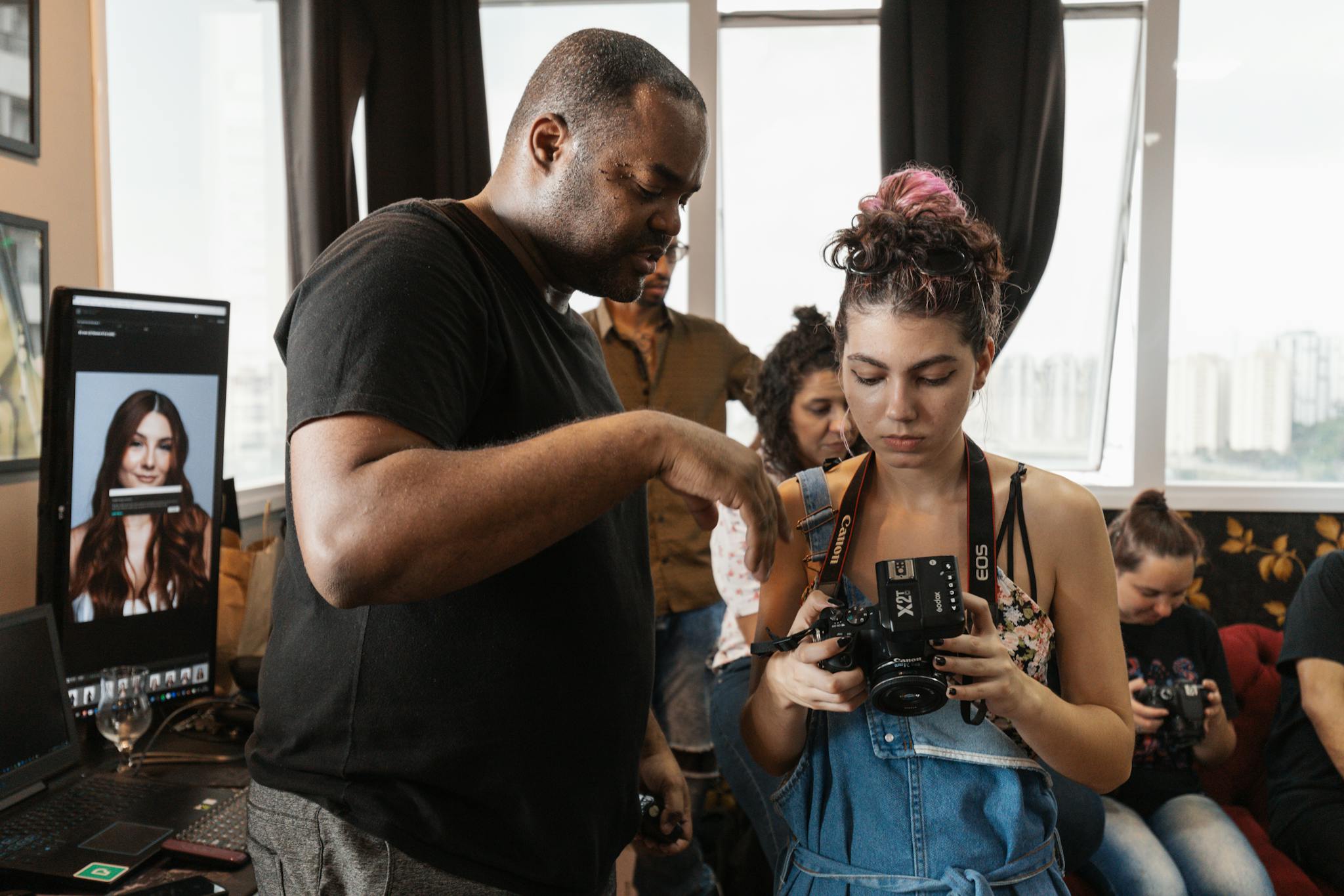 An indoor photography workshop where an instructor guides participants using a DSLR camera.